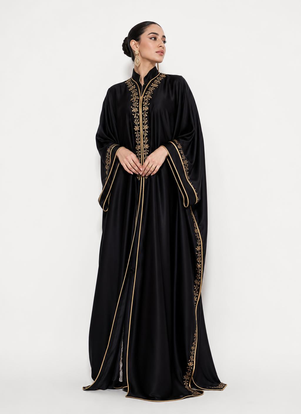 Femme portant une robe longue noire satinée avec broderies dorées